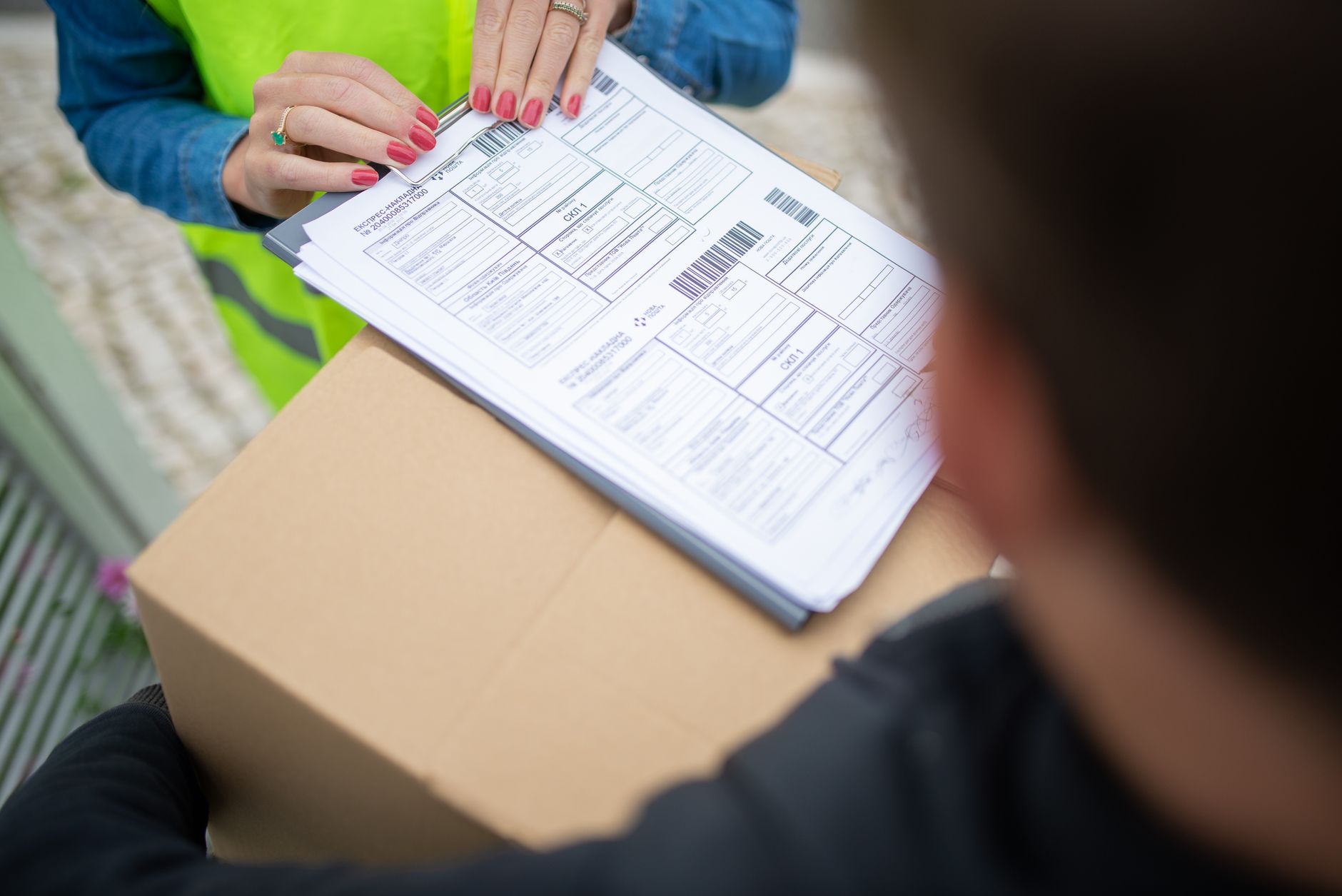 Carta de anuência: o que é e para que serve Courier hands over a package for delivery with signing of receipt documents.