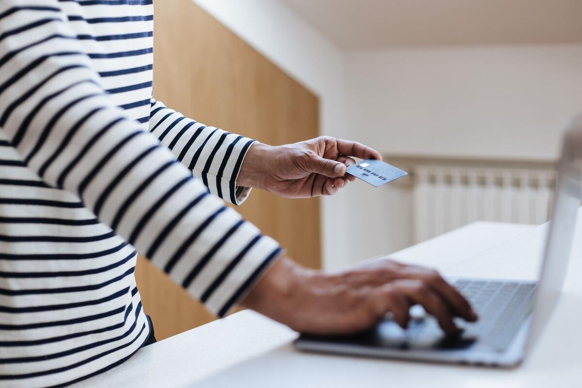 Pessoa usando cartão de crédito para comprar online no notebook