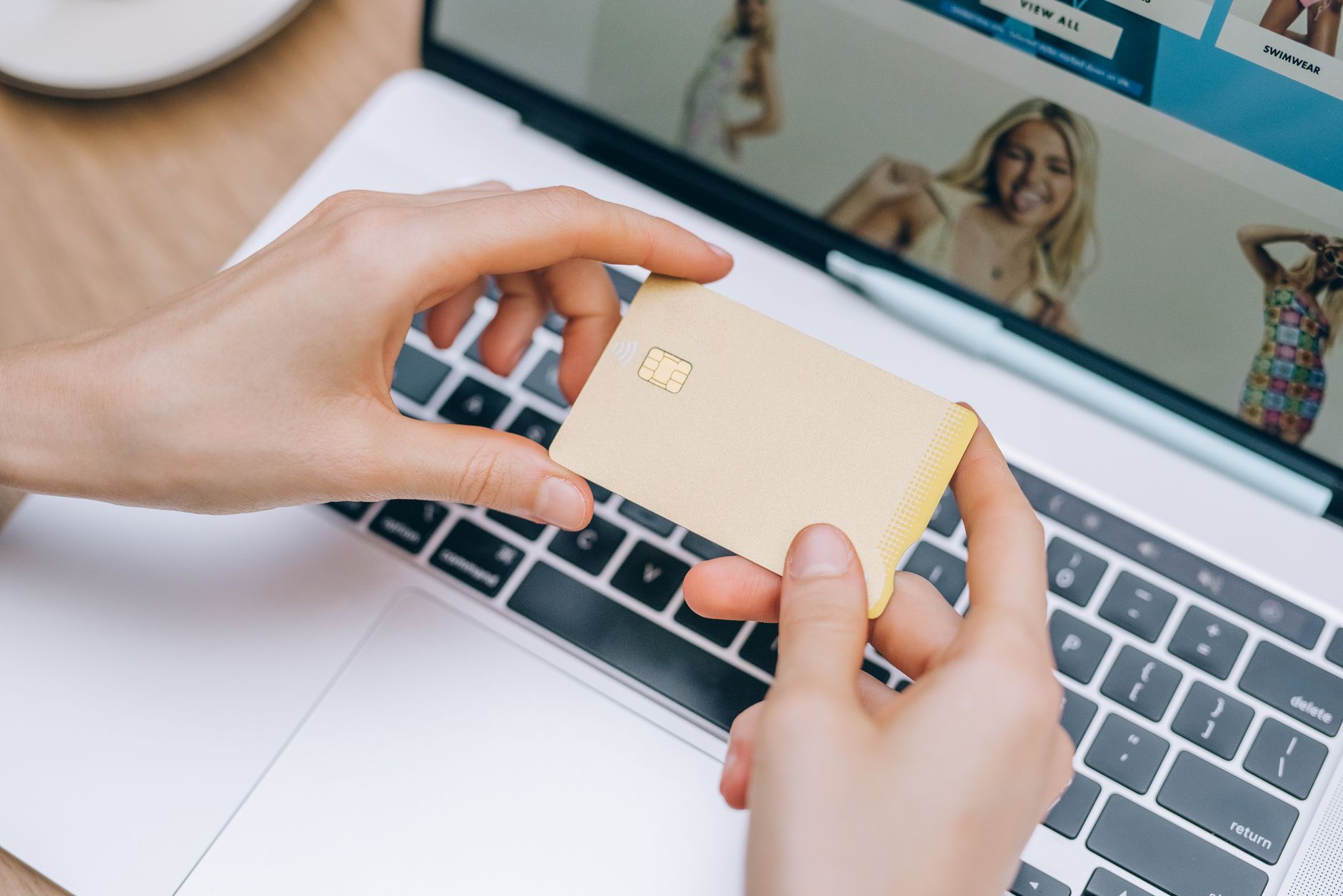 Cartão internacional para negativado: é possível ter? Close-up of hands holding credit card for online shopping on a laptop. Perfect for e-commerce and finance visuals.