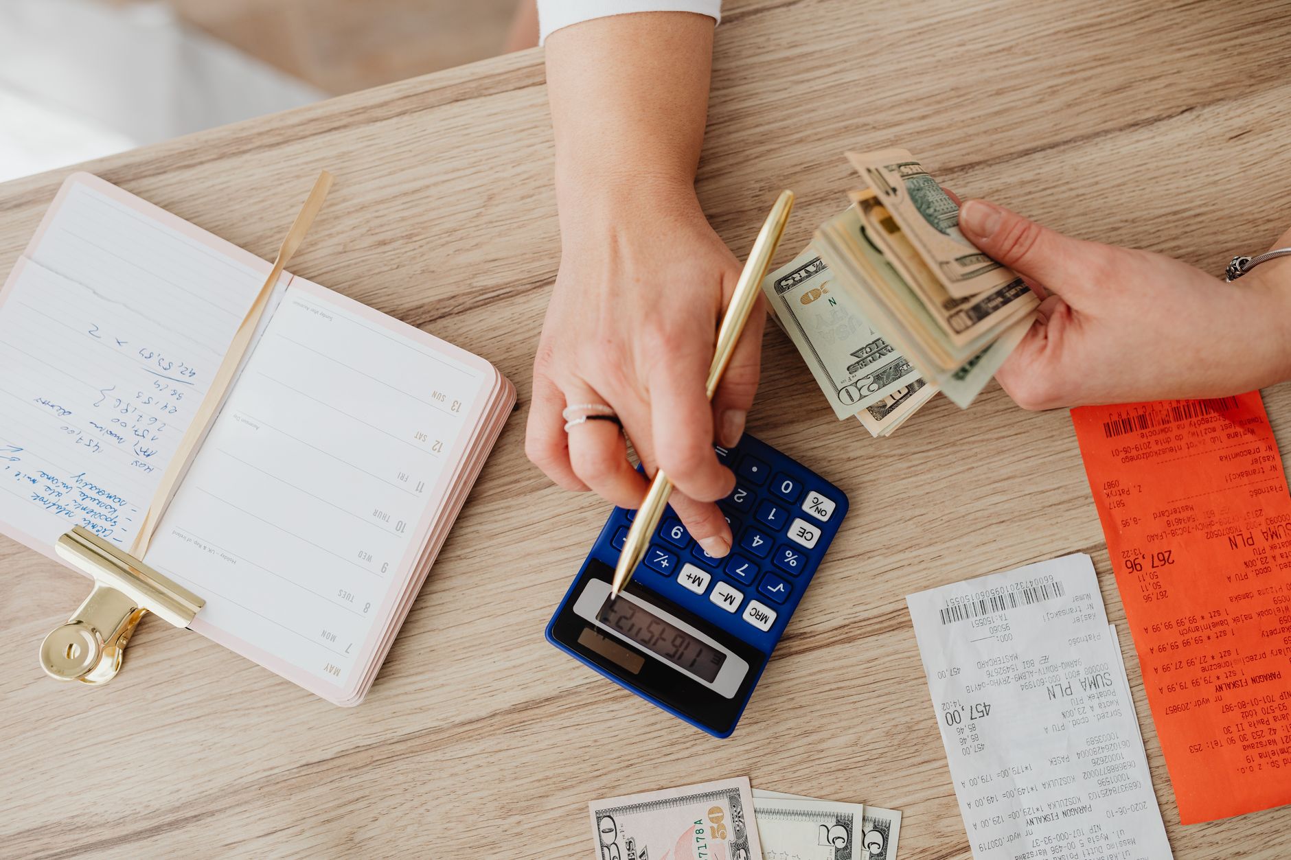 Cartão pré-pago para negativado: como funciona Hands managing finances with calculator, cash, and receipts on a wooden table. Ideal for budgeting concepts.