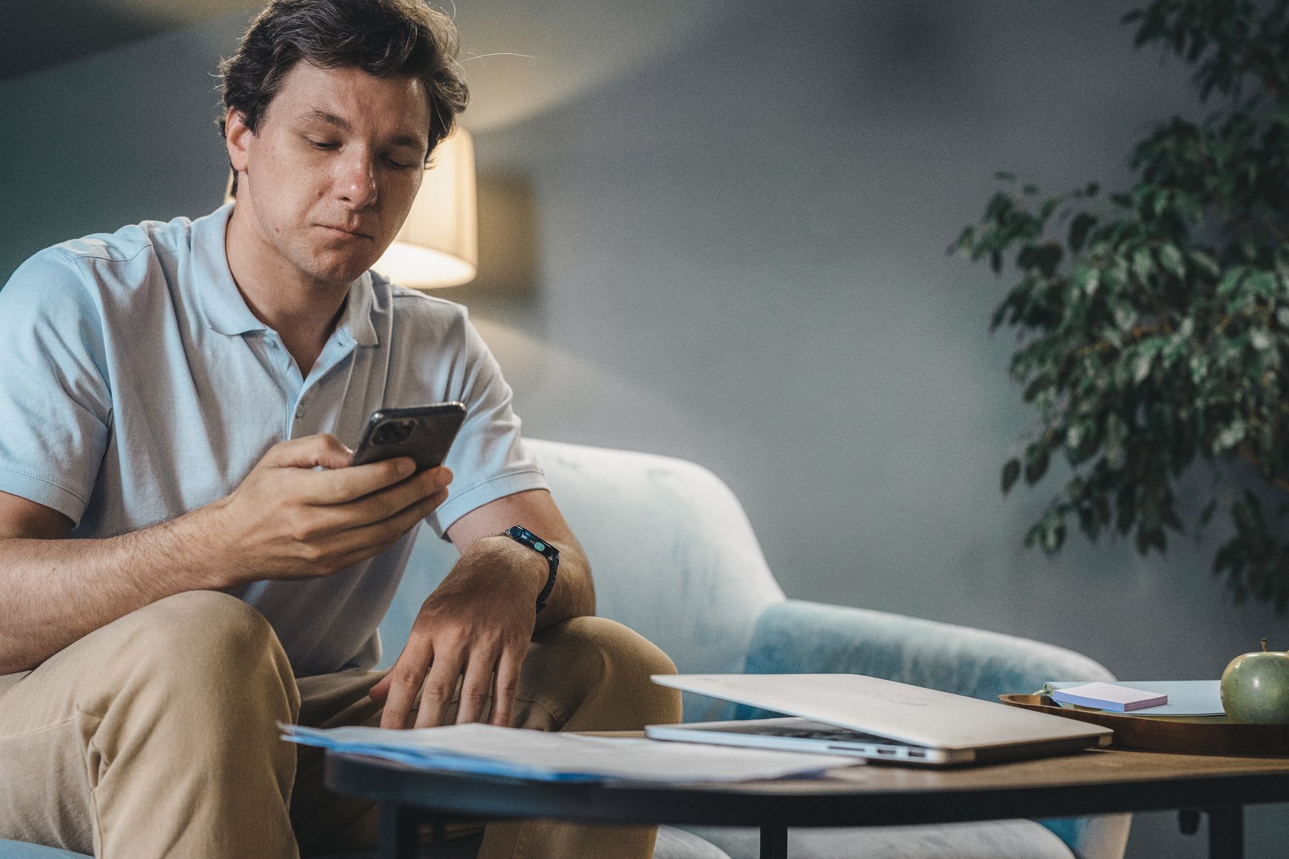 A man engages with his phone while sitting on a sofa in a modern living room.