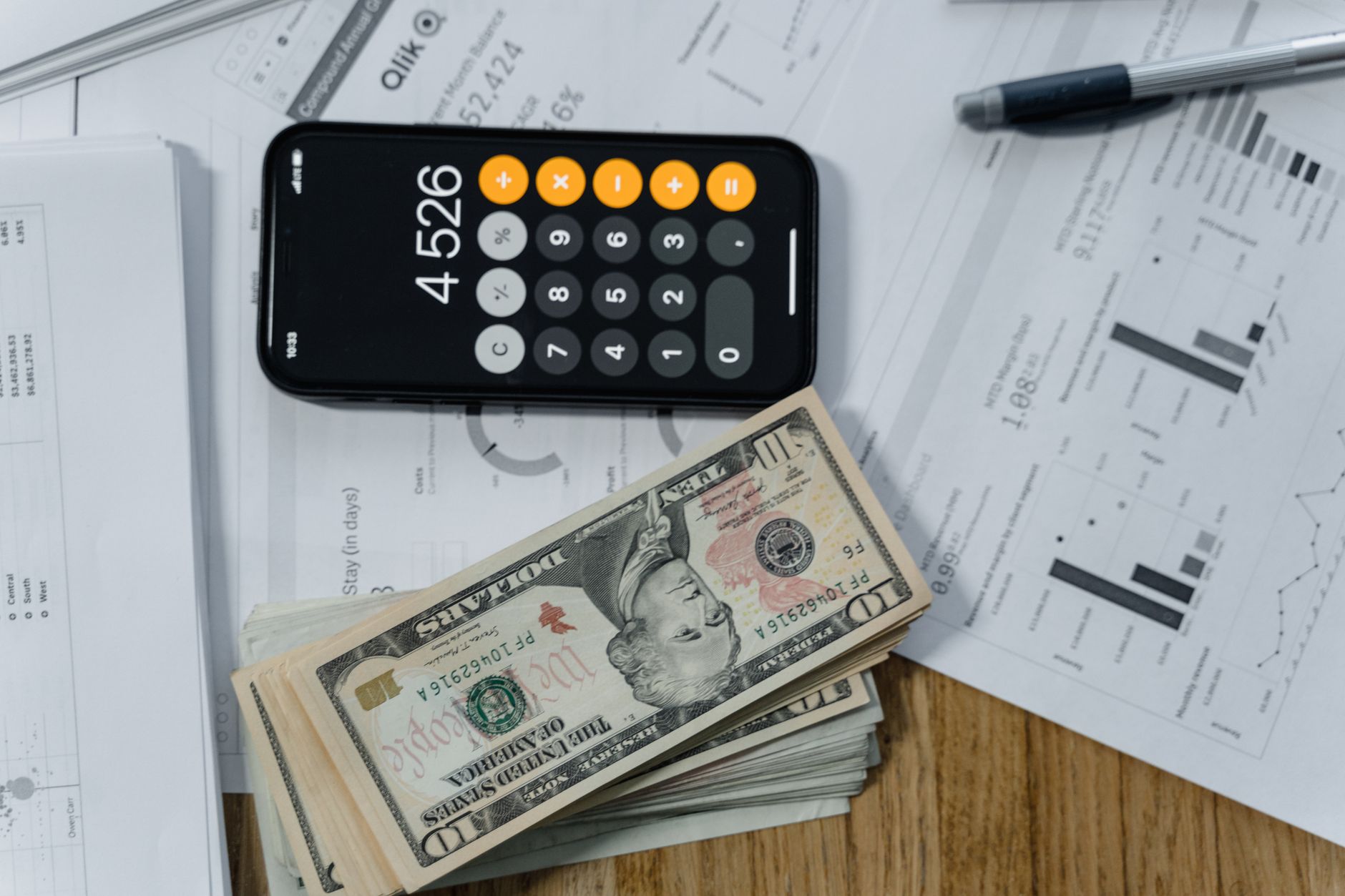 Como calcular a parcela de um empréstimo antes de contratar Mobile calculator, cash, and financial documents on a desk, indicating business planning.