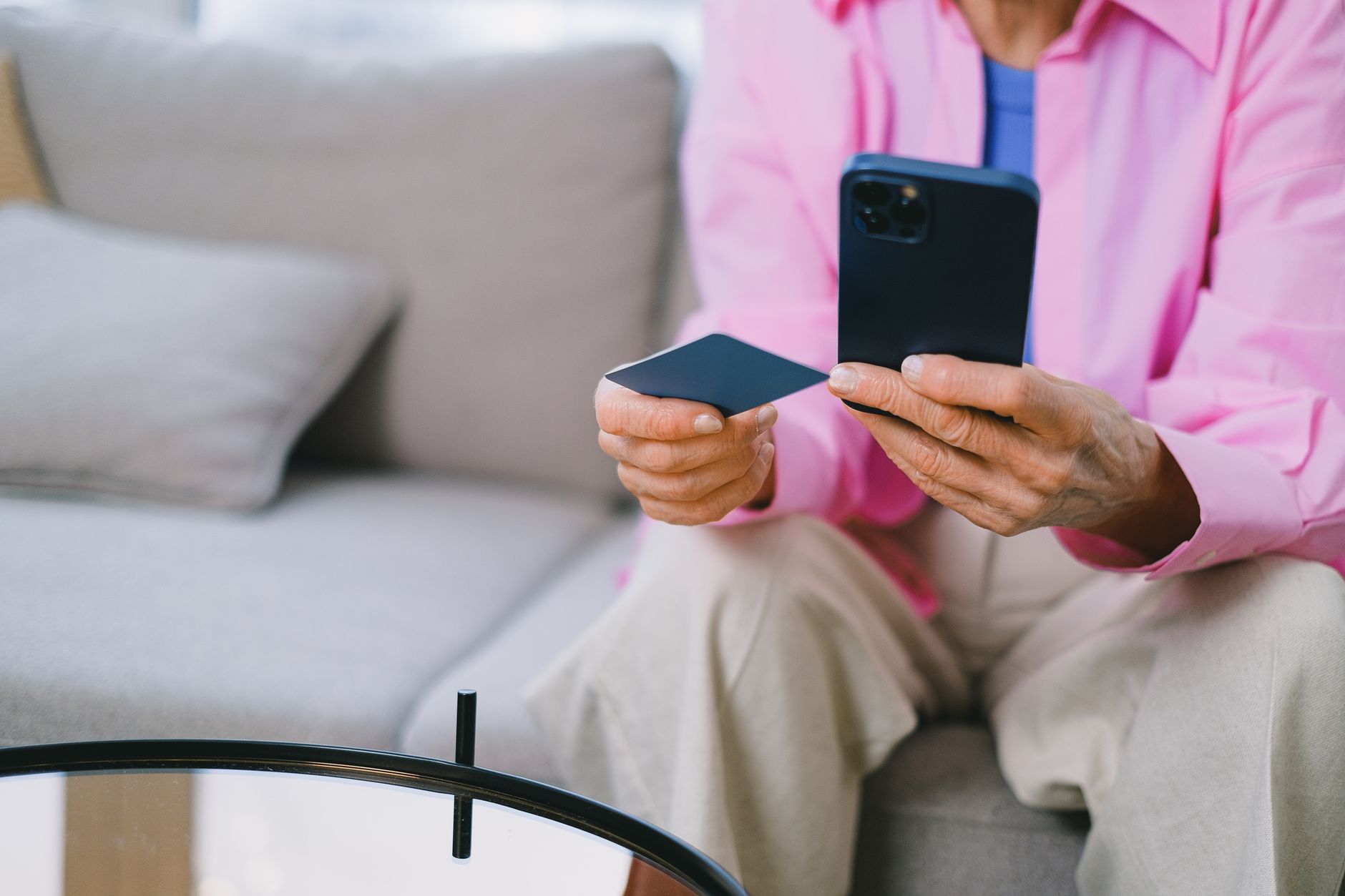 Como consultar seu score de crédito de graça Elderly person making an online payment with credit card using smartphone, seated indoors.