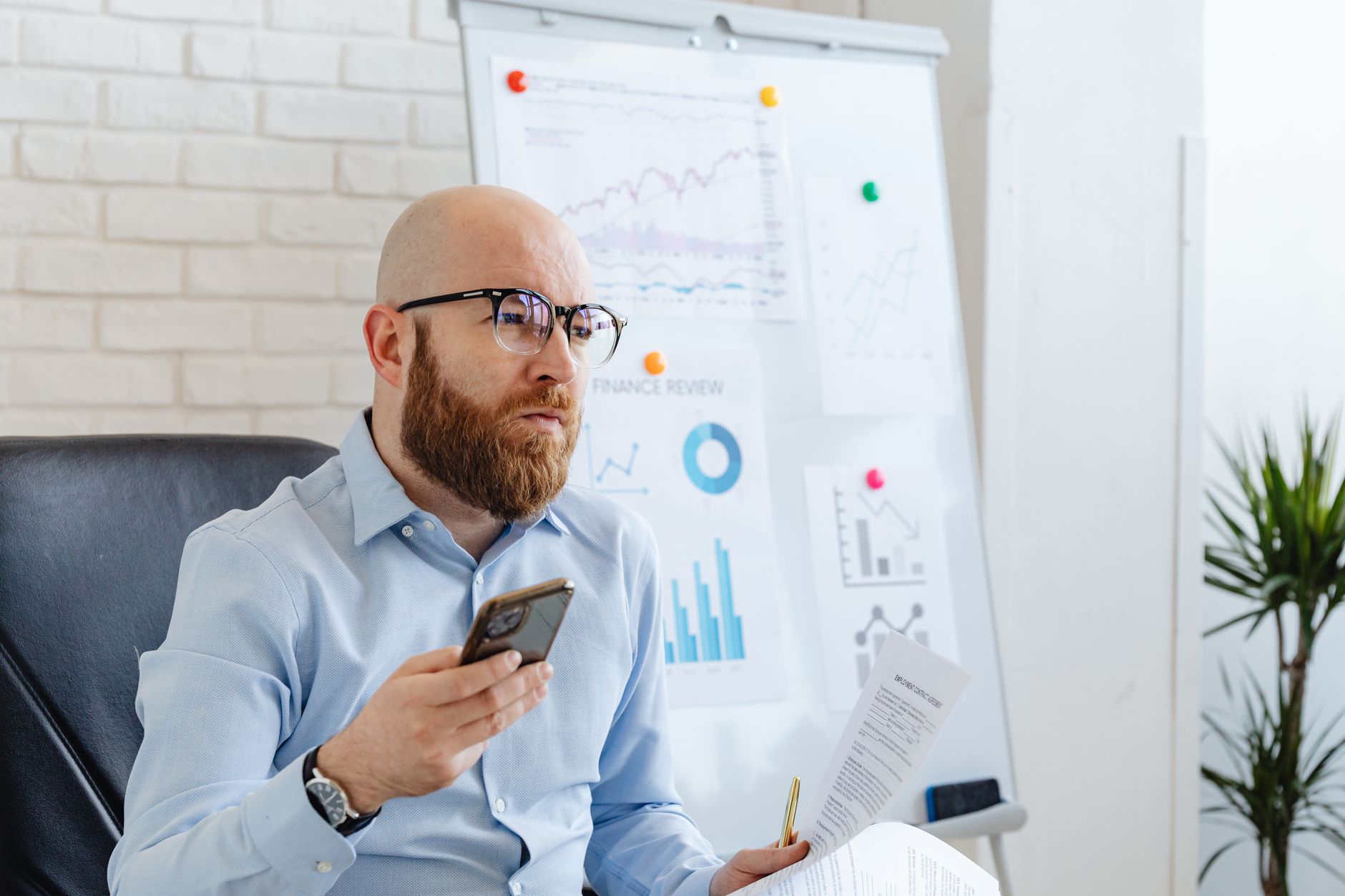 Como funciona o score da Boa Vista e por que ele diverge Bald man with eyeglasses reviews financial data in office with diagrams.