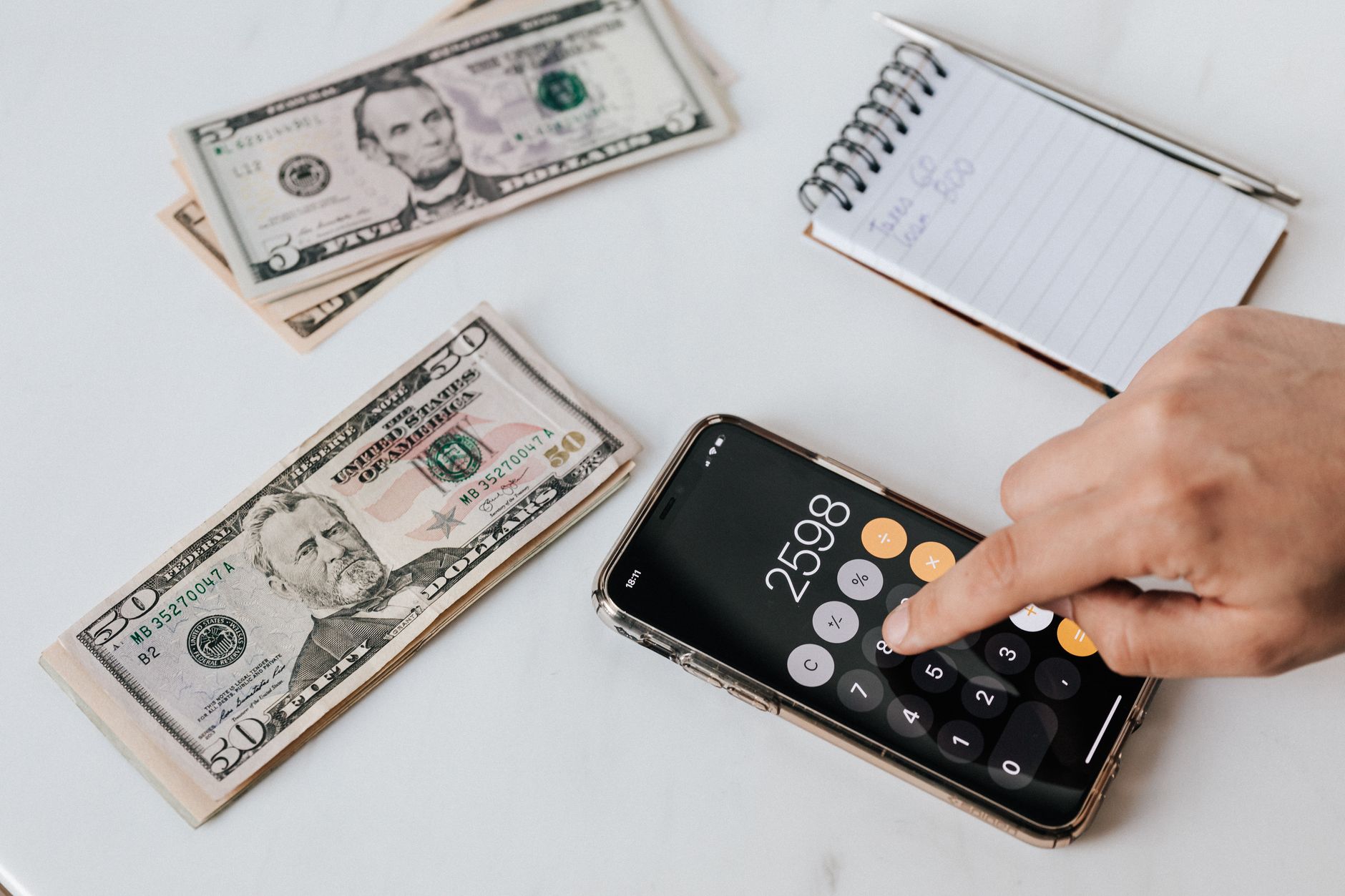 Como negociar uma dívida que está no Serasa From above of crop anonymous economist calculating total amount of income using calculator app on cellphone near piles of greenbacks and notebook with pen