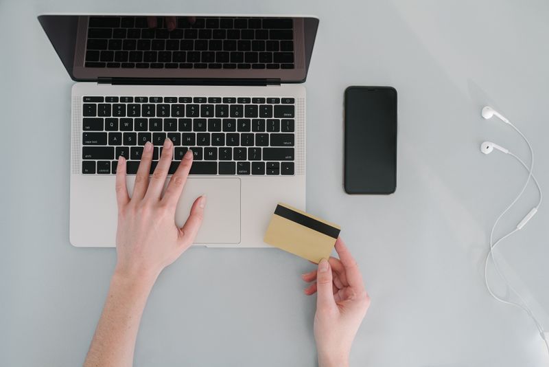 Como negociar dívida por telefone sem cair em golpe Flat lay of a workspace with a laptop, bank card, smartphone, and earphones, ideal for online finance themes.