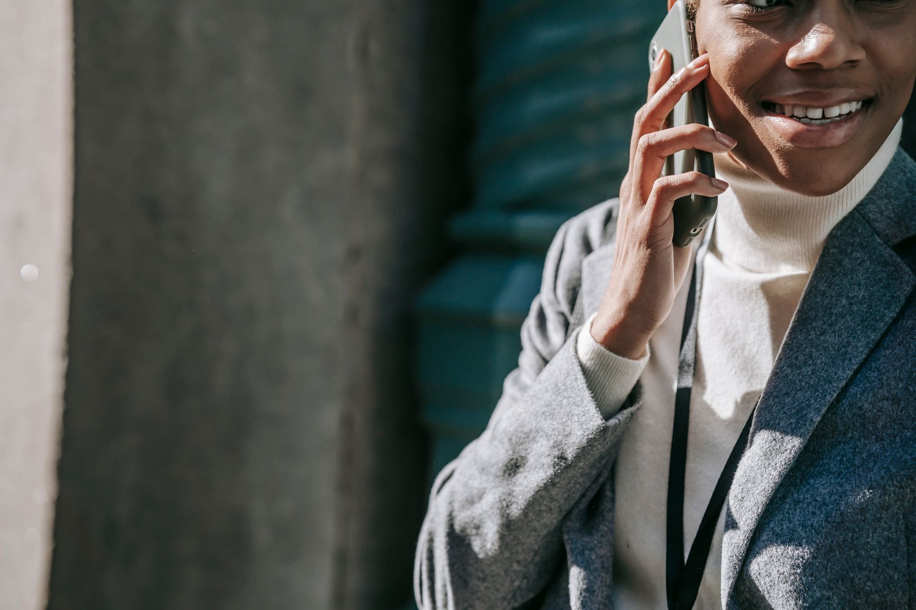 Como negociar uma dívida vencida há vários anos Crop cheerful young African American woman in elegant clothes smiling while talking on smartphone on street on sunny day