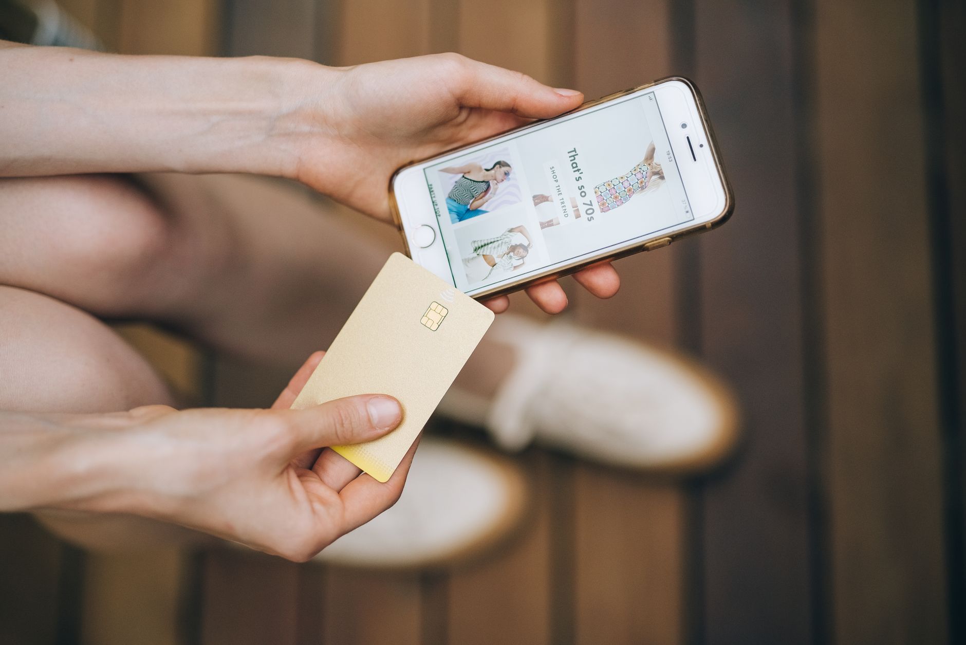 Como parar de gastar por impulso e evitar novas dívidas Hands holding smartphone and credit card for online shopping on a wooden floor.