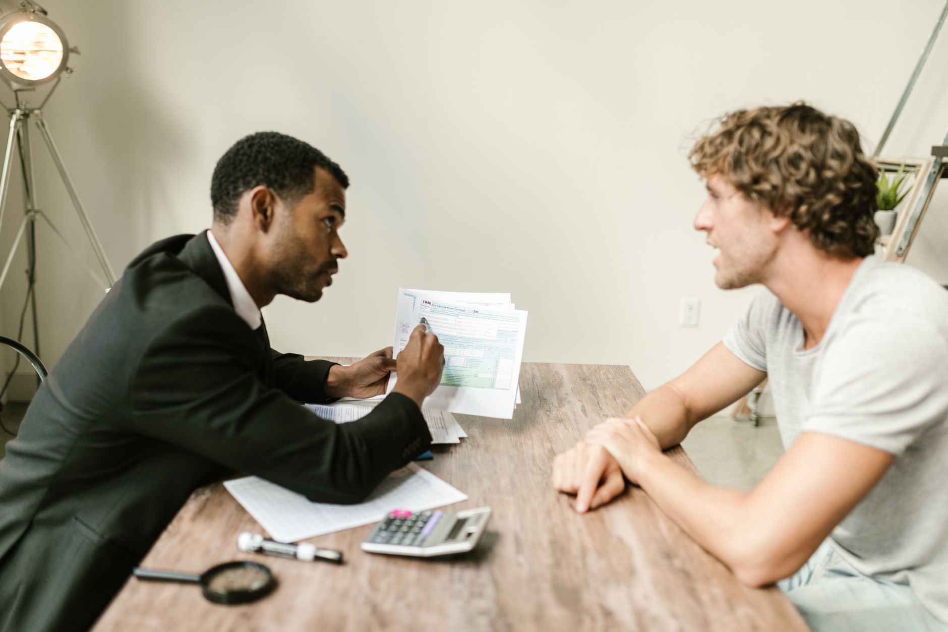 Como sair das dívidas: plano prático passo a passo A financial advisor discusses paperwork with a client at a desk in a modern office.