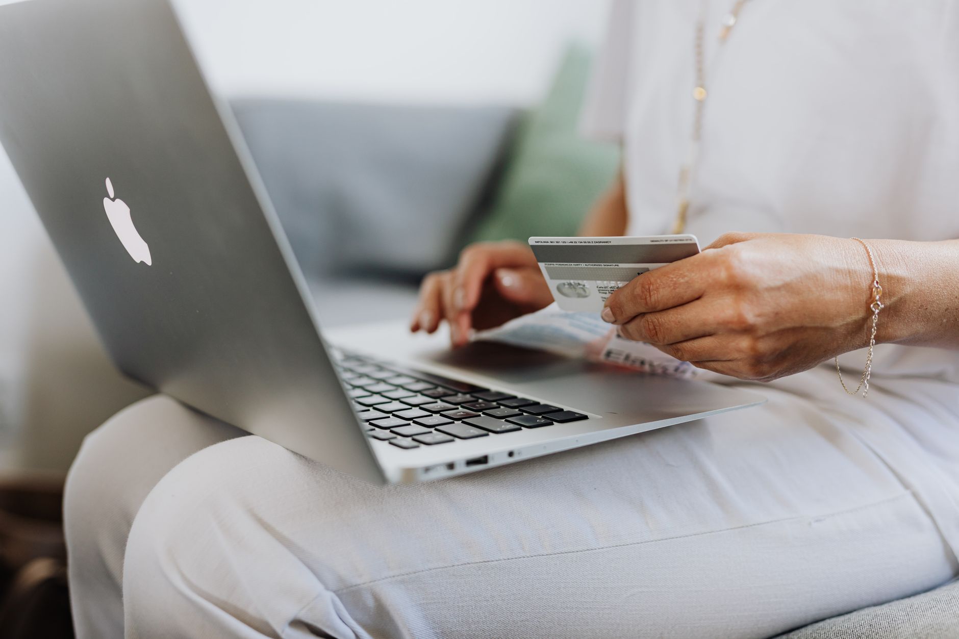 Como sair do SPC: negociar dívida e limpar seu nome Close-up of a person holding a credit card while shopping online using a laptop at home.