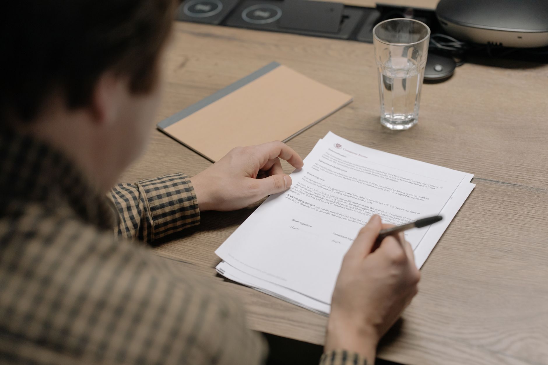 Pessoa conferindo documentos e o extrato de um benefício social sobre a mesa