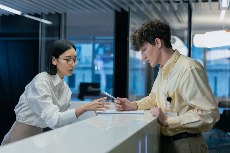 Two professionals discussing at a modern reception, highlighting teamwork and customer service.