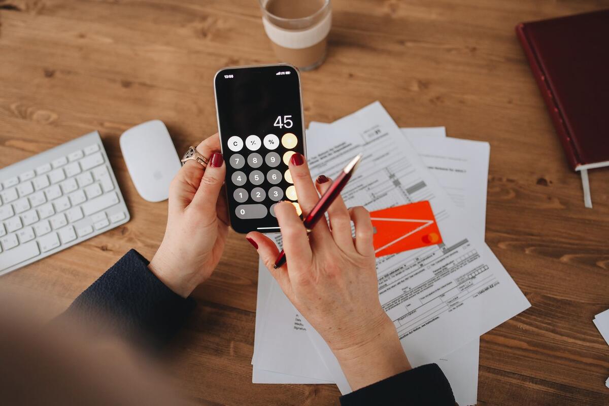 A consulta feita pelas empresas é diferente Mãos usando a calculadora do celular sobre documentos financeiros
