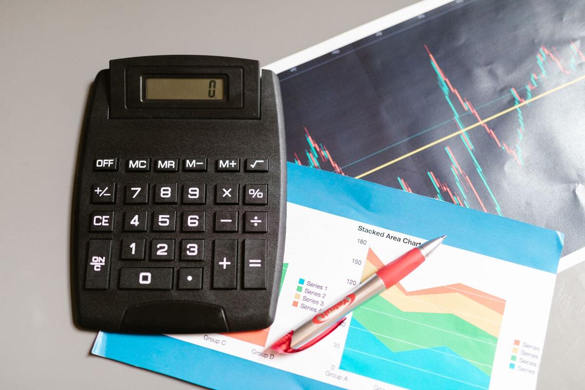 O que realmente faz o score subir Calculadora e caneta sobre gráficos financeiros impressos