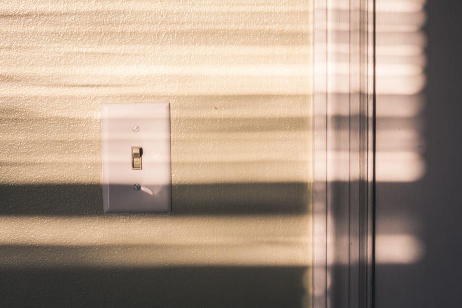 Interruptor de luz em uma parede com sombras de persiana