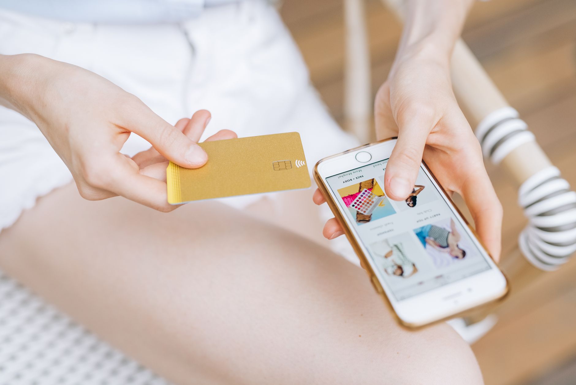 Cartão pré-pago ou débito: qual é a diferença? Close-up of a woman holding a smartphone and credit card for online shopping. Modern e-commerce concept.
