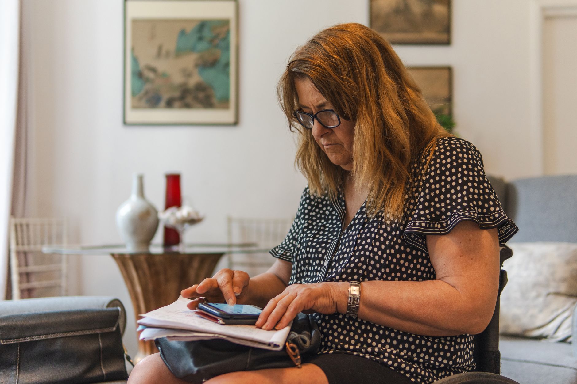 Direito de resposta no Serasa e no SPC: como pedir A middle-aged woman in a polka dot dress focused on her smartphone in a cozy living room setting.