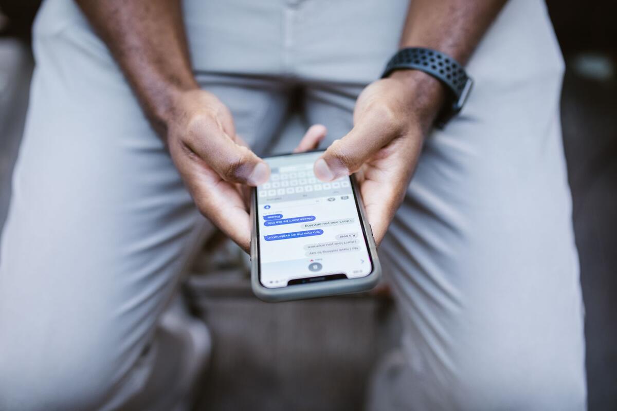 Mãos segurando um celular com mensagens na tela