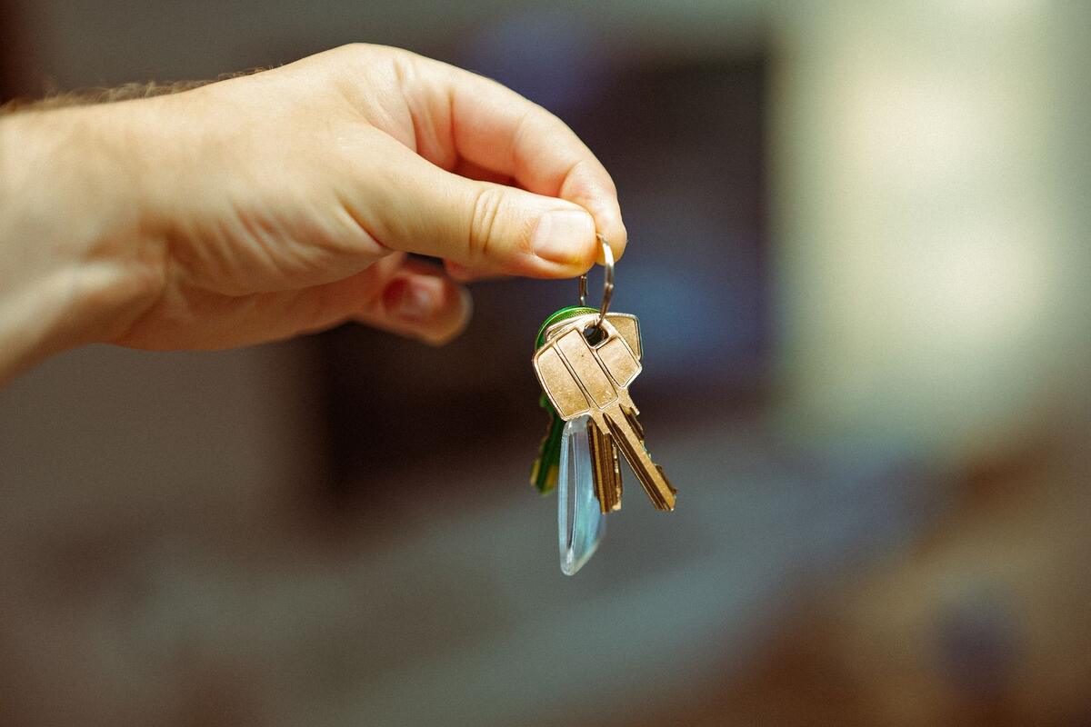 Mão segurando chaveiro com várias chaves de apartamento