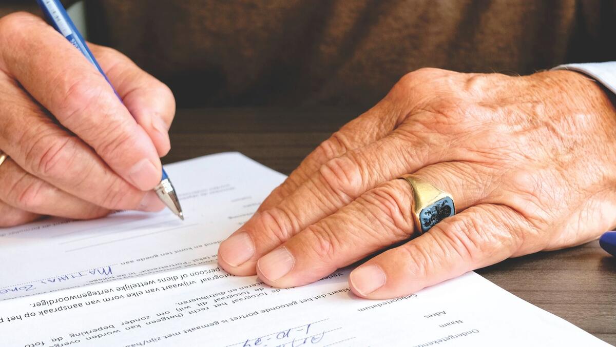 Pessoa idosa assinando documento legal