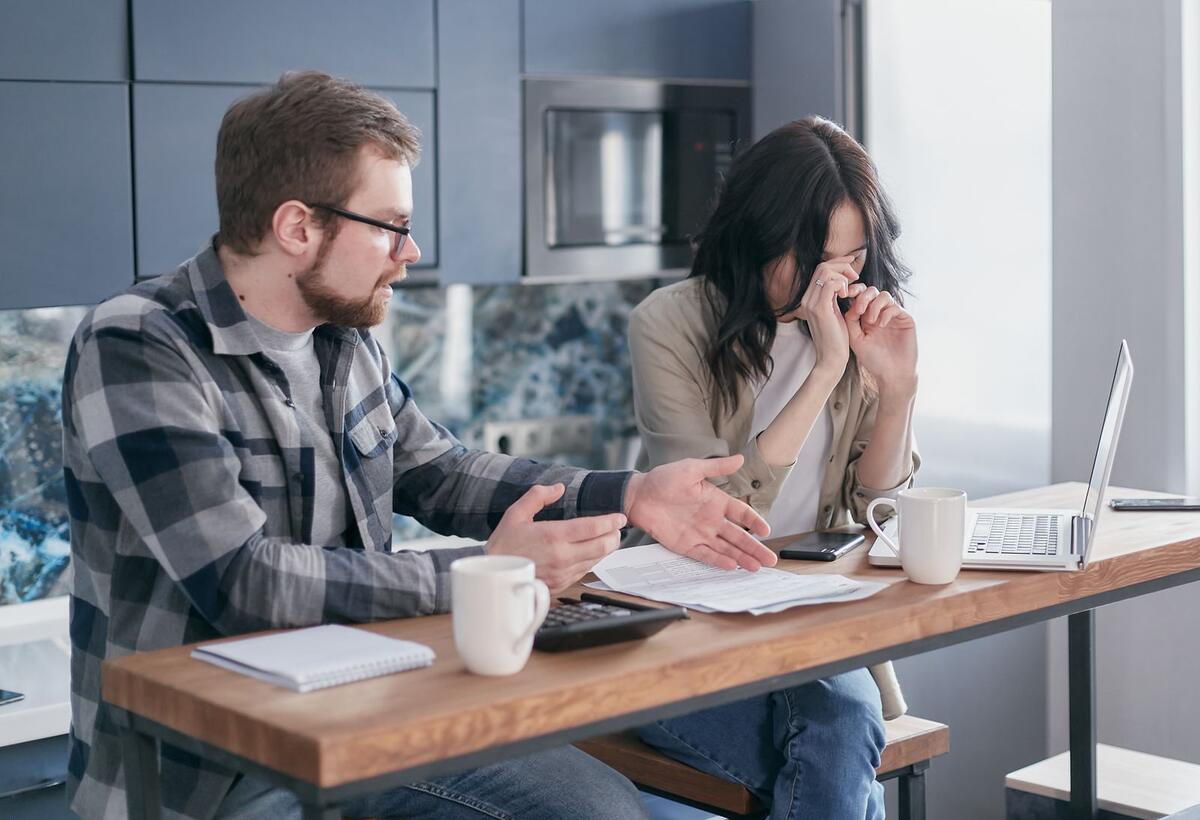 O que acontece quando o Fies atrasa Casal preocupado analisando contas e dívidas na mesa