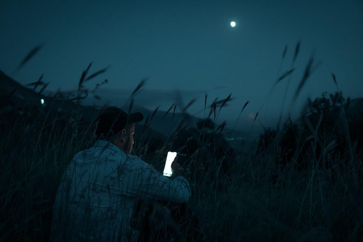 Homem usando o celular à noite sozinho