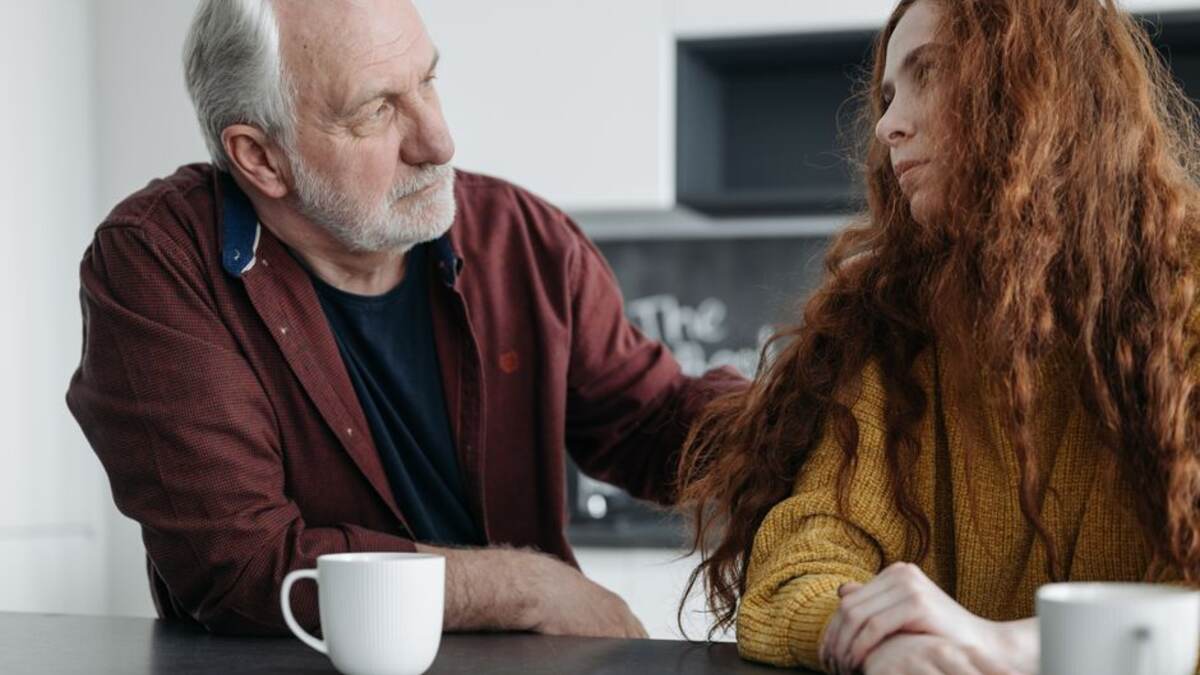 Homem mais velho sendo acolhido por uma familiar à mesa