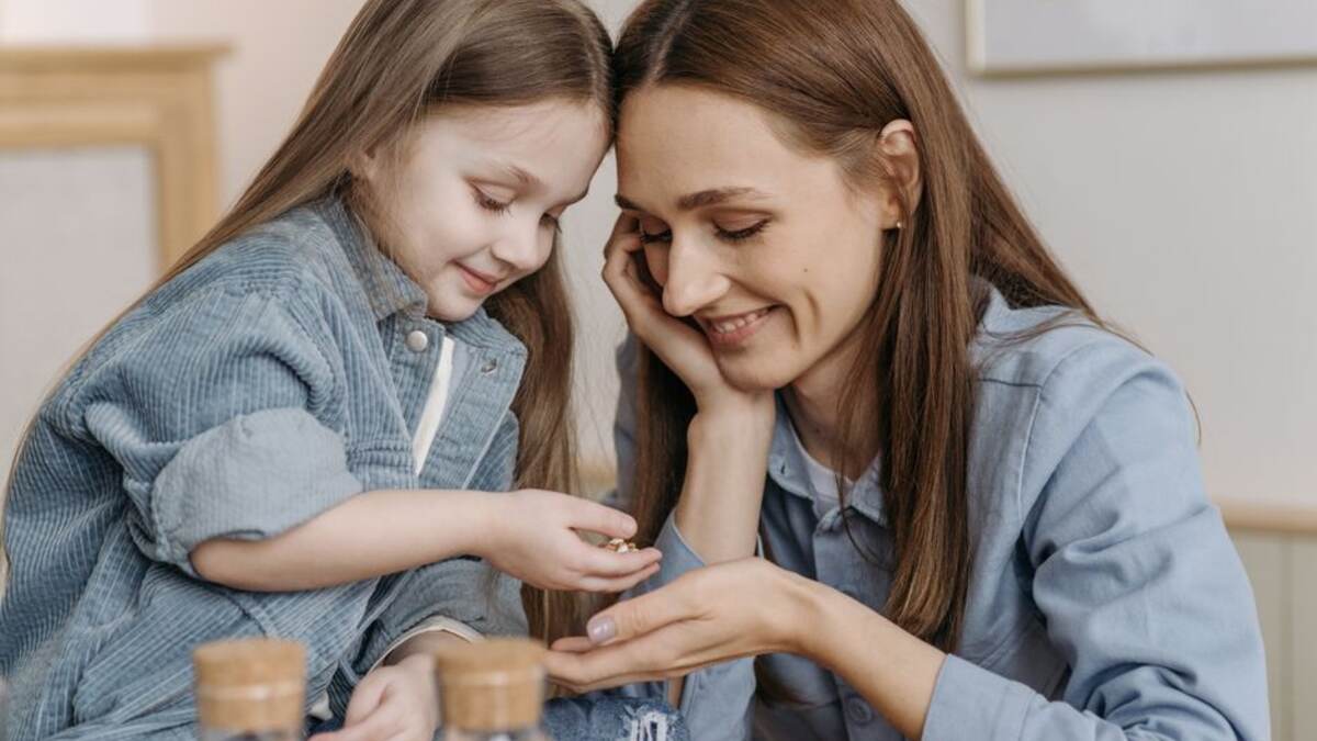 Mãe e filho colocando moedas em um cofrinho