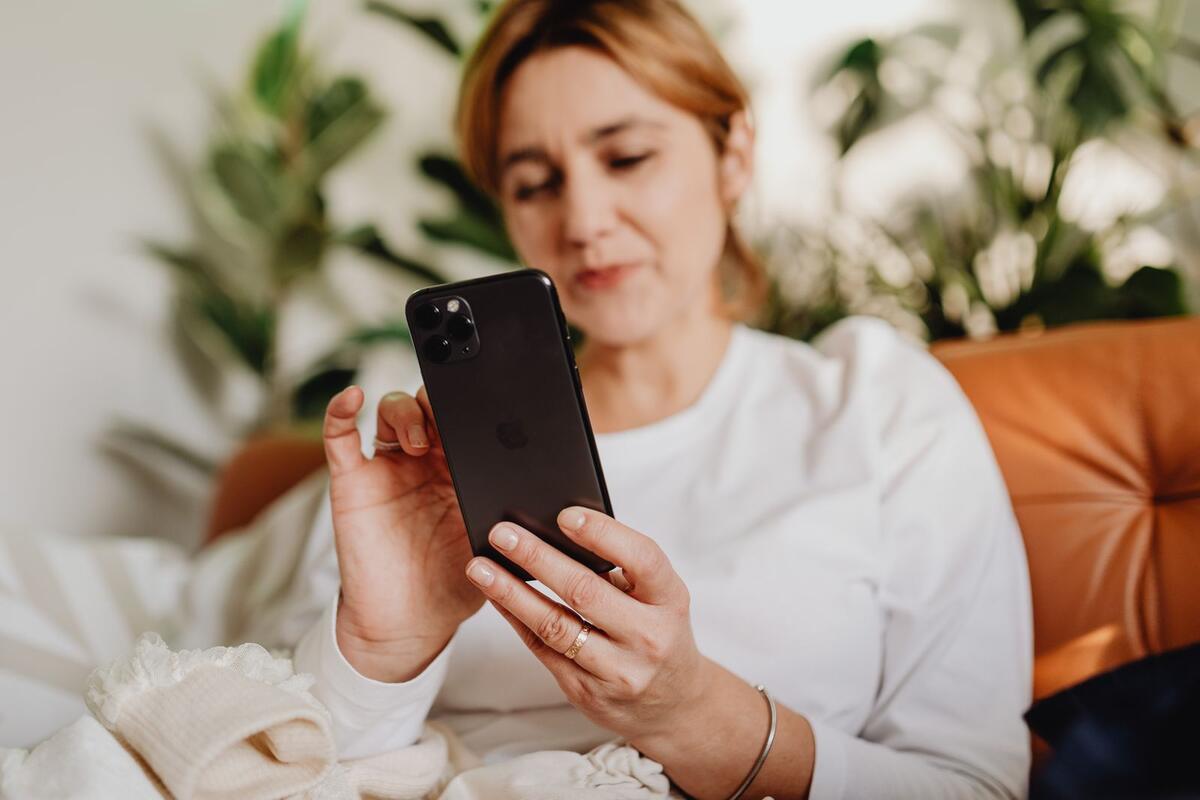 Mulher sentada em casa lendo informações no celular