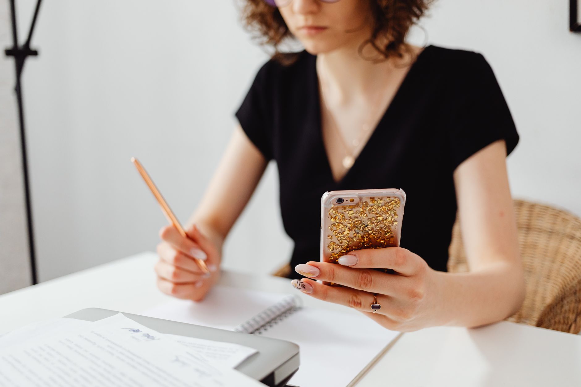Empréstimo online para negativado: como solicitar Professional woman multitasking with smartphone and notes at desk in office setting.