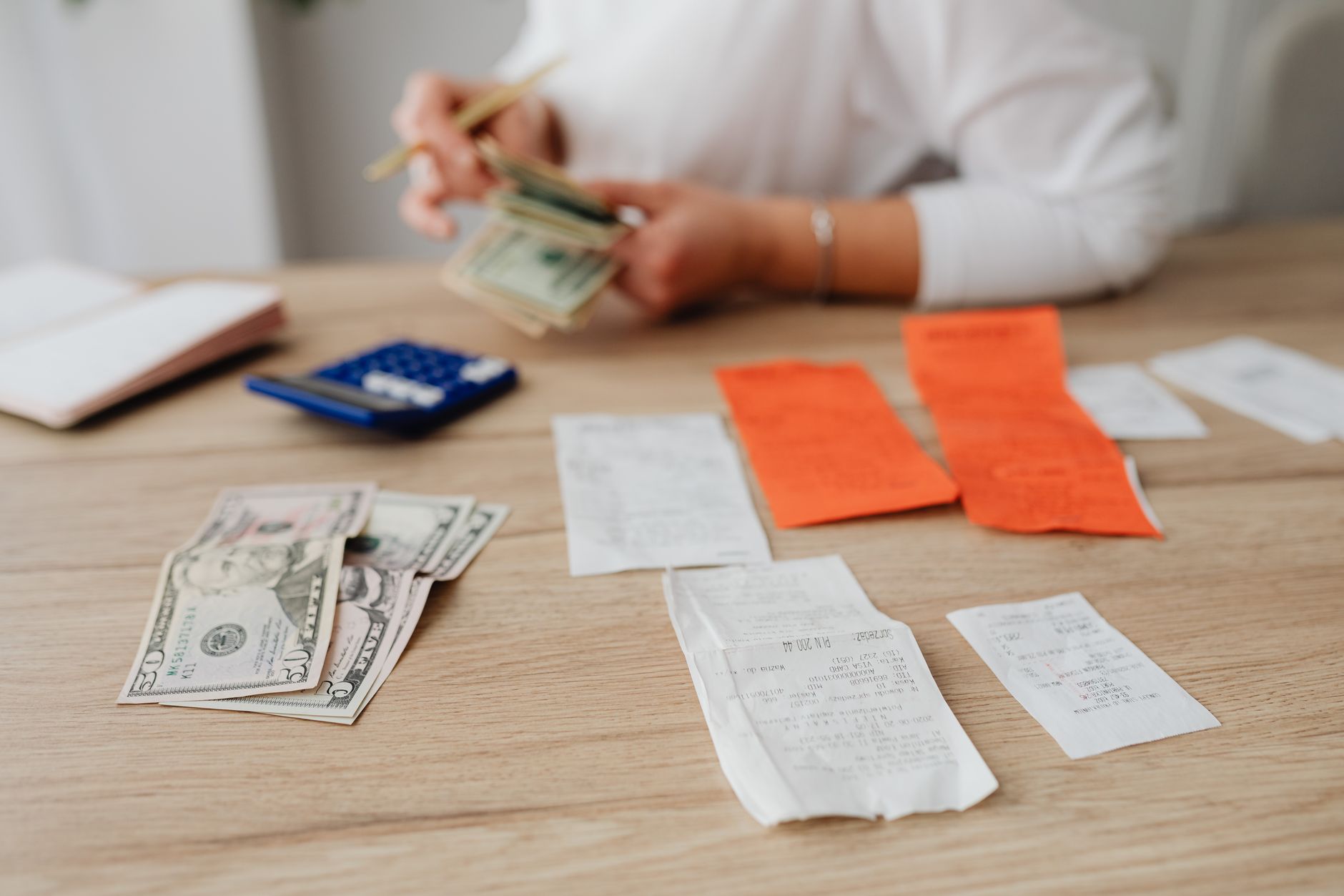 Empréstimo para autônomo negativado: como comprovar renda A person using a calculator and cash to plan a household budget.