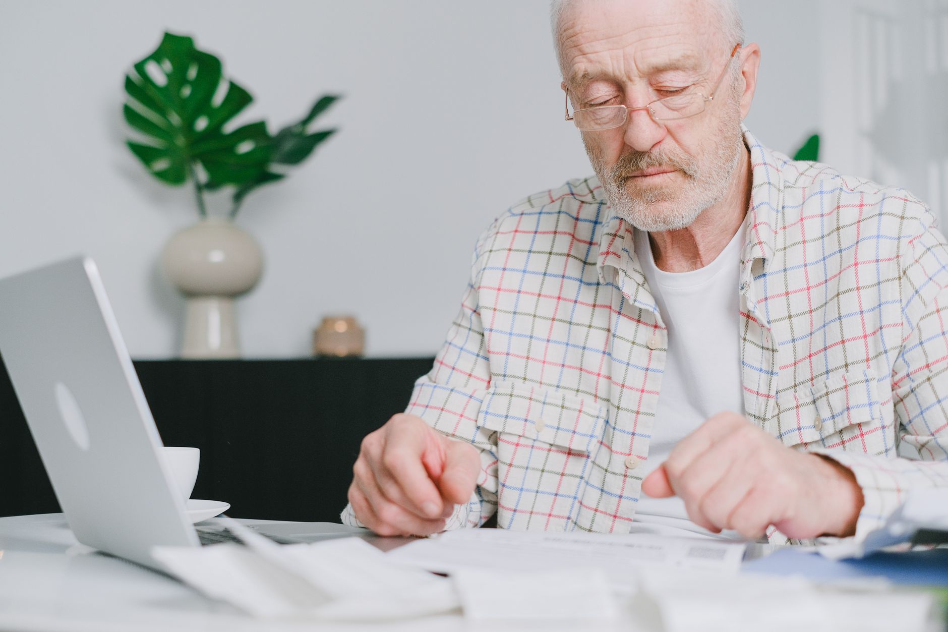 Aposentado analisando documentos e contas em uma mesa de casa