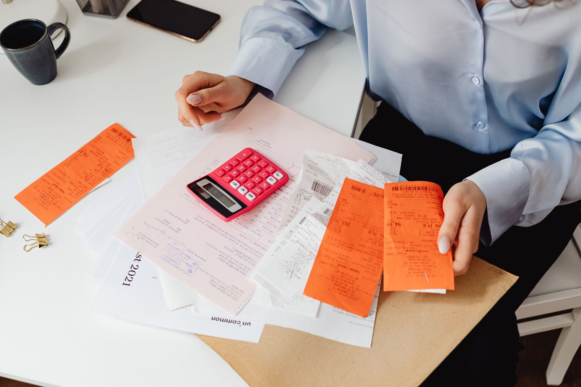 Pessoa conferindo um cheque e contas sobre a mesa de casa