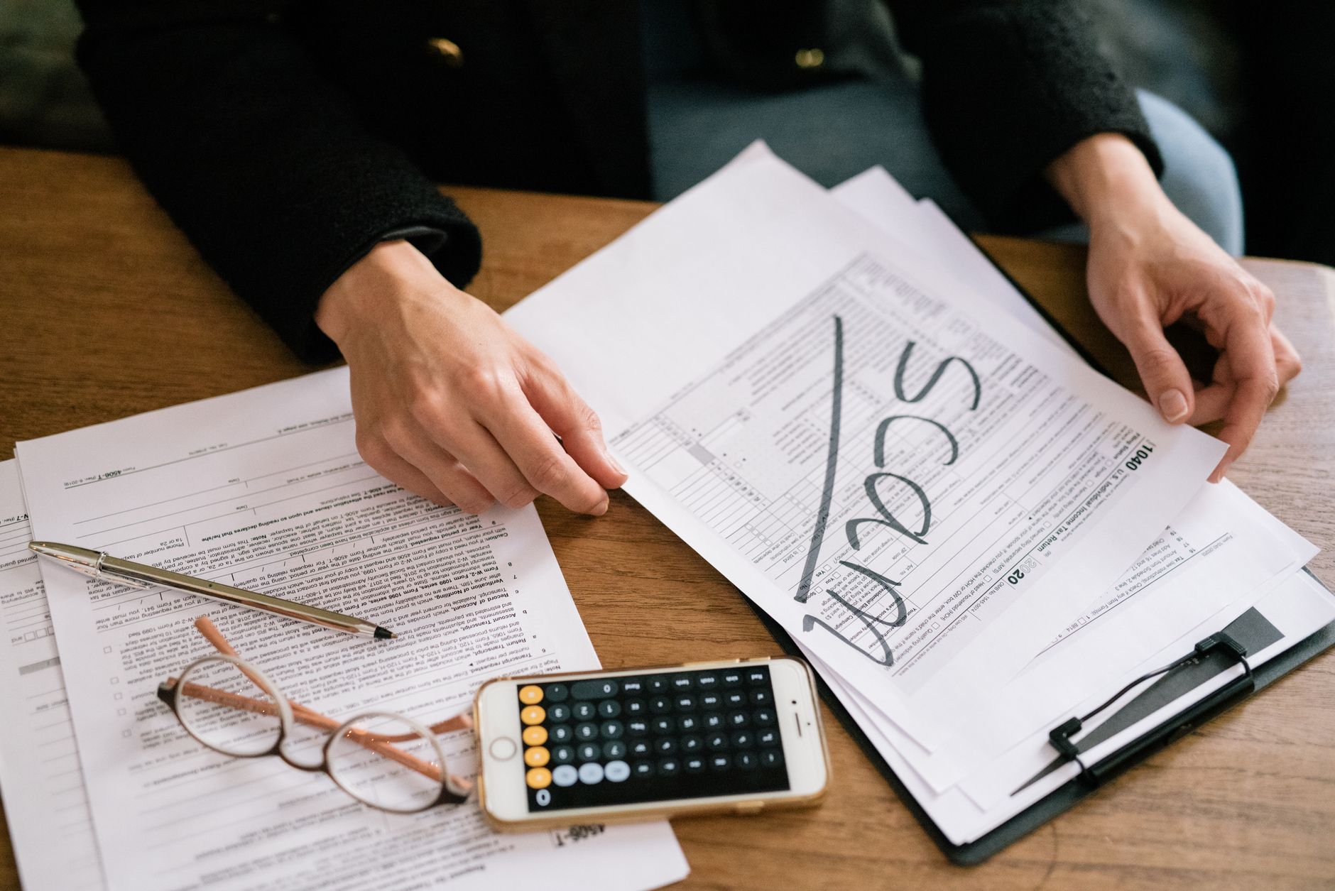 Empréstimo para negativado: como simular a parcela Hands of a person examining tax forms labeled as scam with calculator and papers.