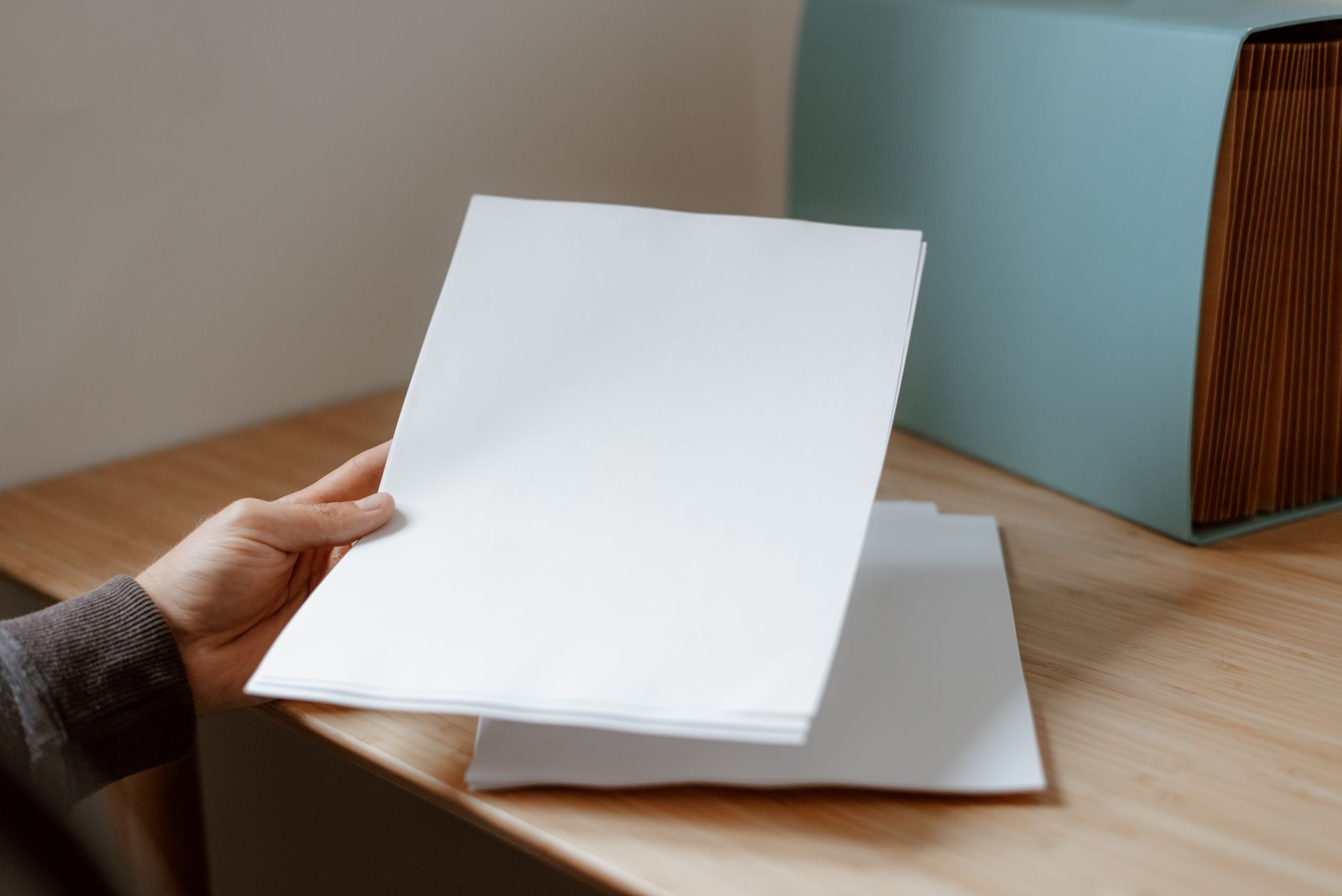 Empréstimo para negativado com valor baixo: como buscar Crop anonymous person demonstrating empty sheet of paper against wooden table with folder for documents