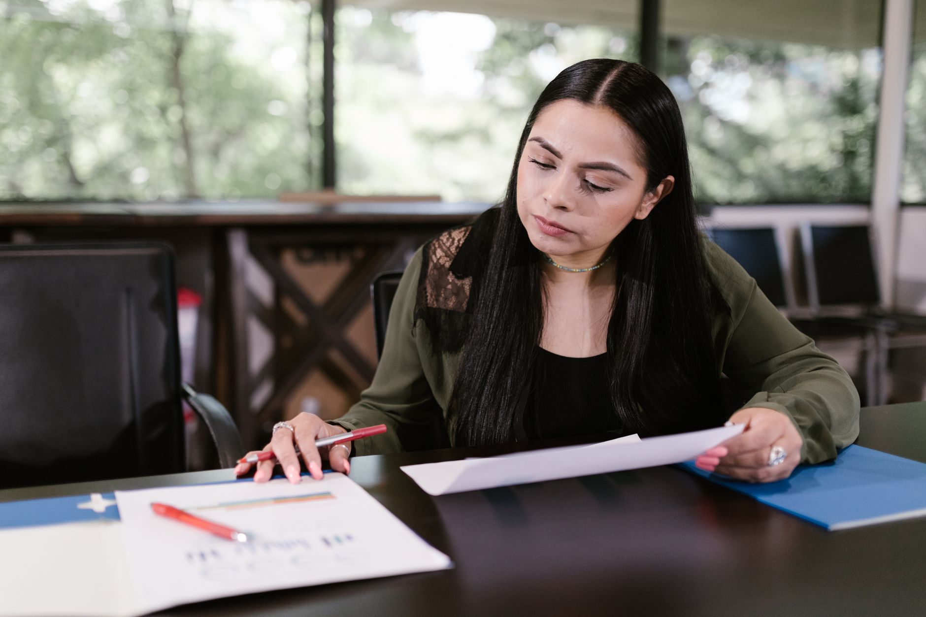 Empréstimo para negativado: como funciona e opções Professional woman in office setting studying documents with concentration.