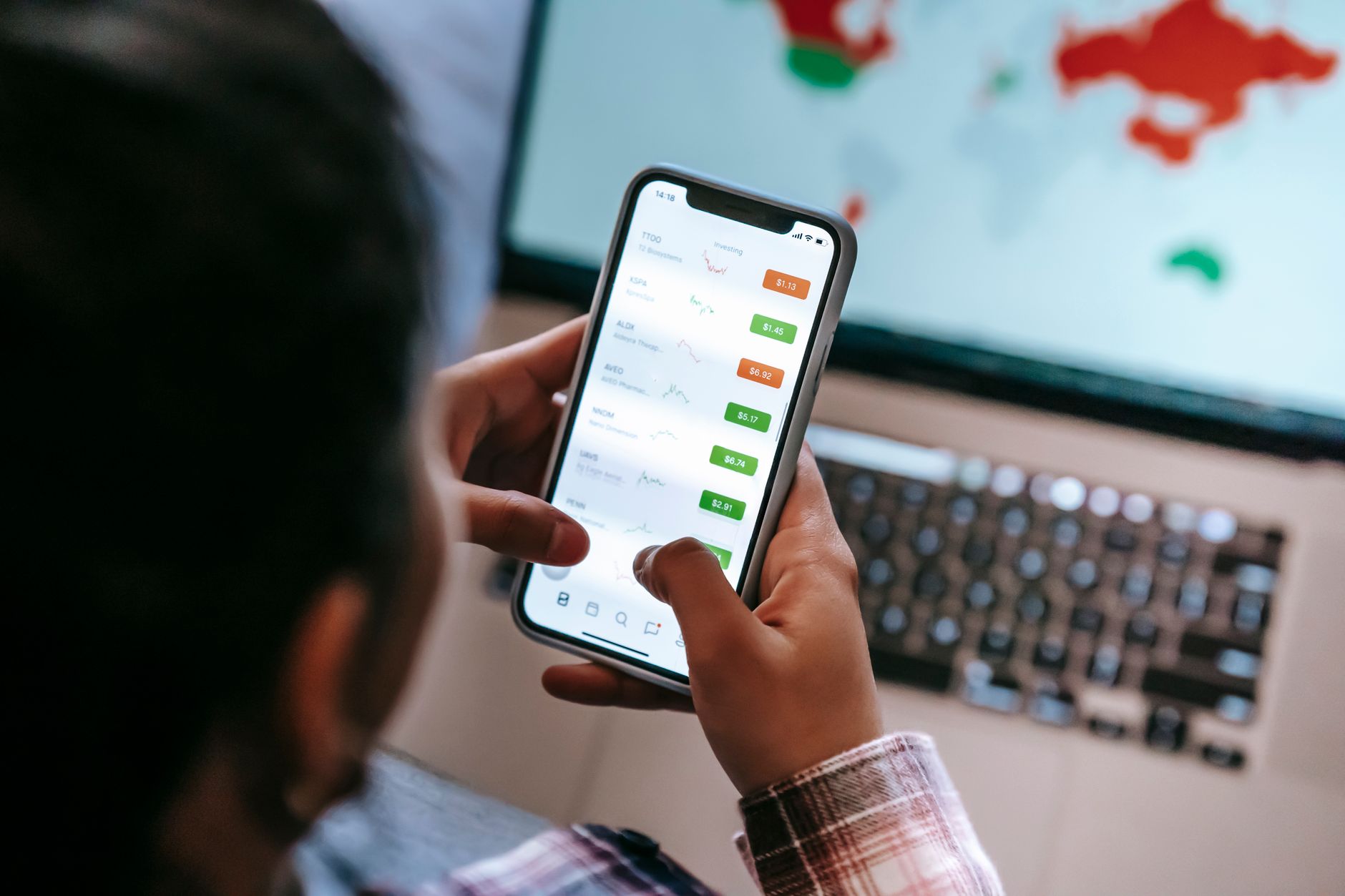Fintech de crédito para negativado: como funciona From above of crop anonymous dealer touching screen on cellphone with financial exchange application against netbook