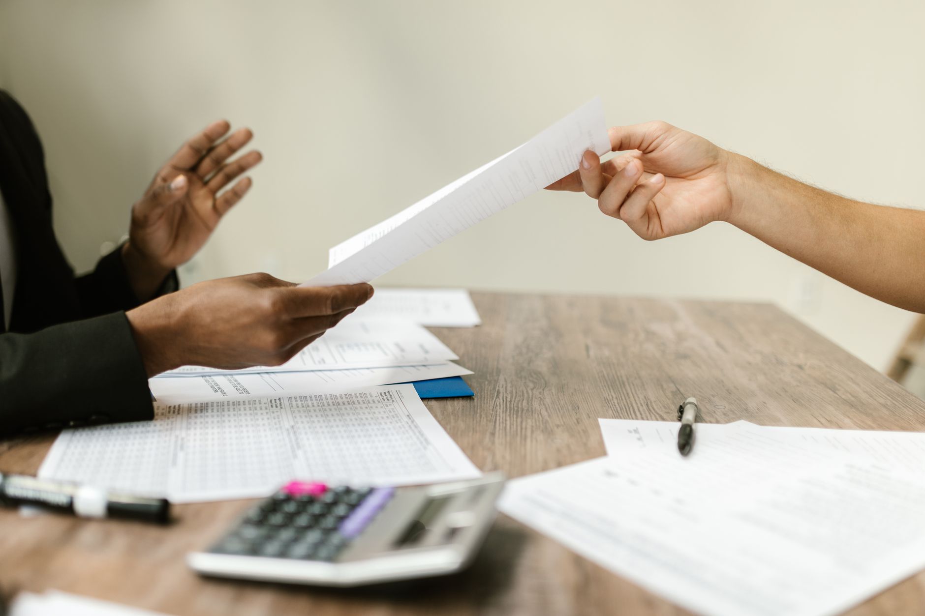 Golpe do empréstimo fácil: como identificar antes de cair Two professionals exchanging documents in a corporate setting, emphasizing collaboration and paperwork.