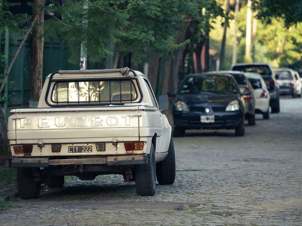 Carro estacionado em rua de paralelepípedo arborizada