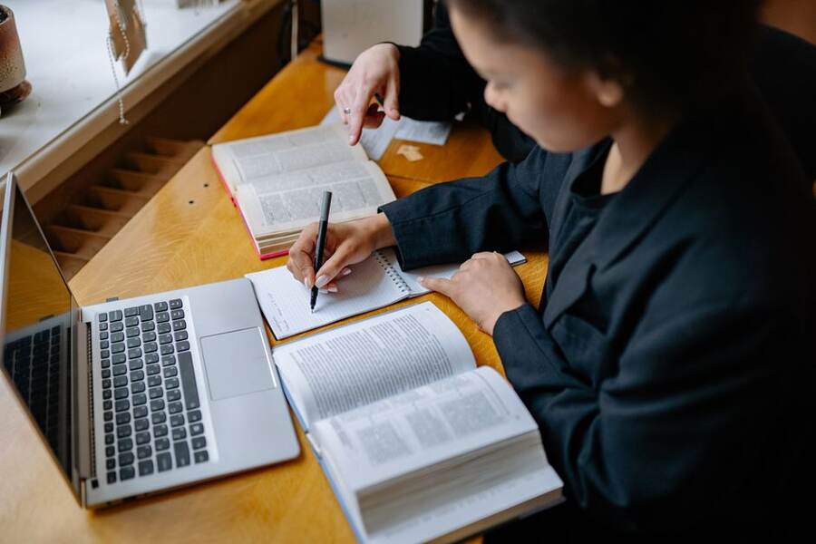 Estudante anotando em um caderno ao lado do notebook Estudante anotando em um caderno ao lado do notebook