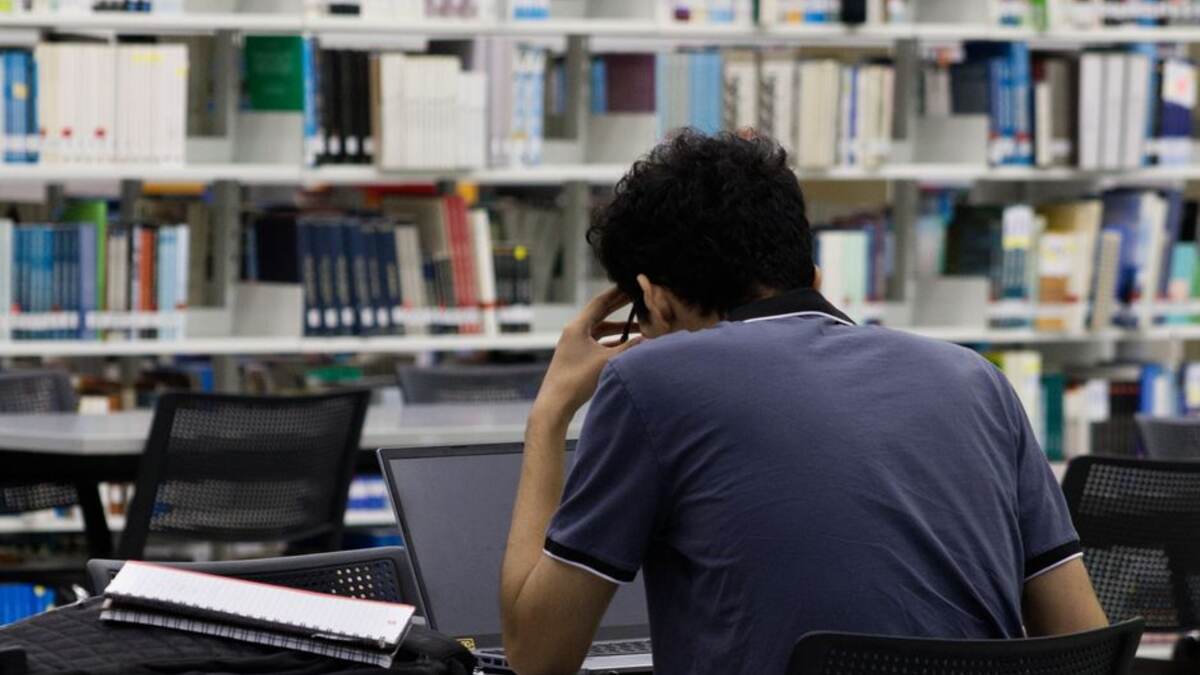 Estudante pensativa com notebook em uma biblioteca universitária
