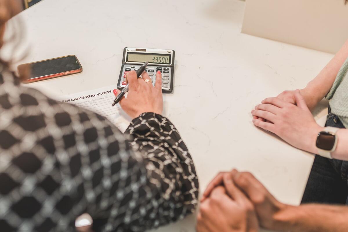 O que aumenta a chance de aprovação Pessoas conferindo contrato com calculadora sobre a mesa