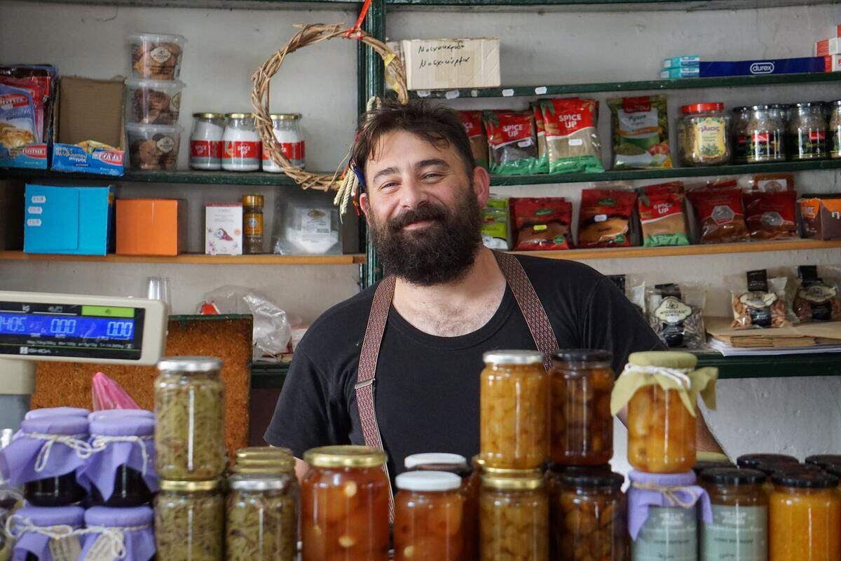 Comerciante sorridente atrás do balcão de uma loja de conservas caseiras