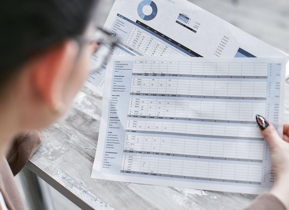 Mulher analisando uma planilha financeira impressa