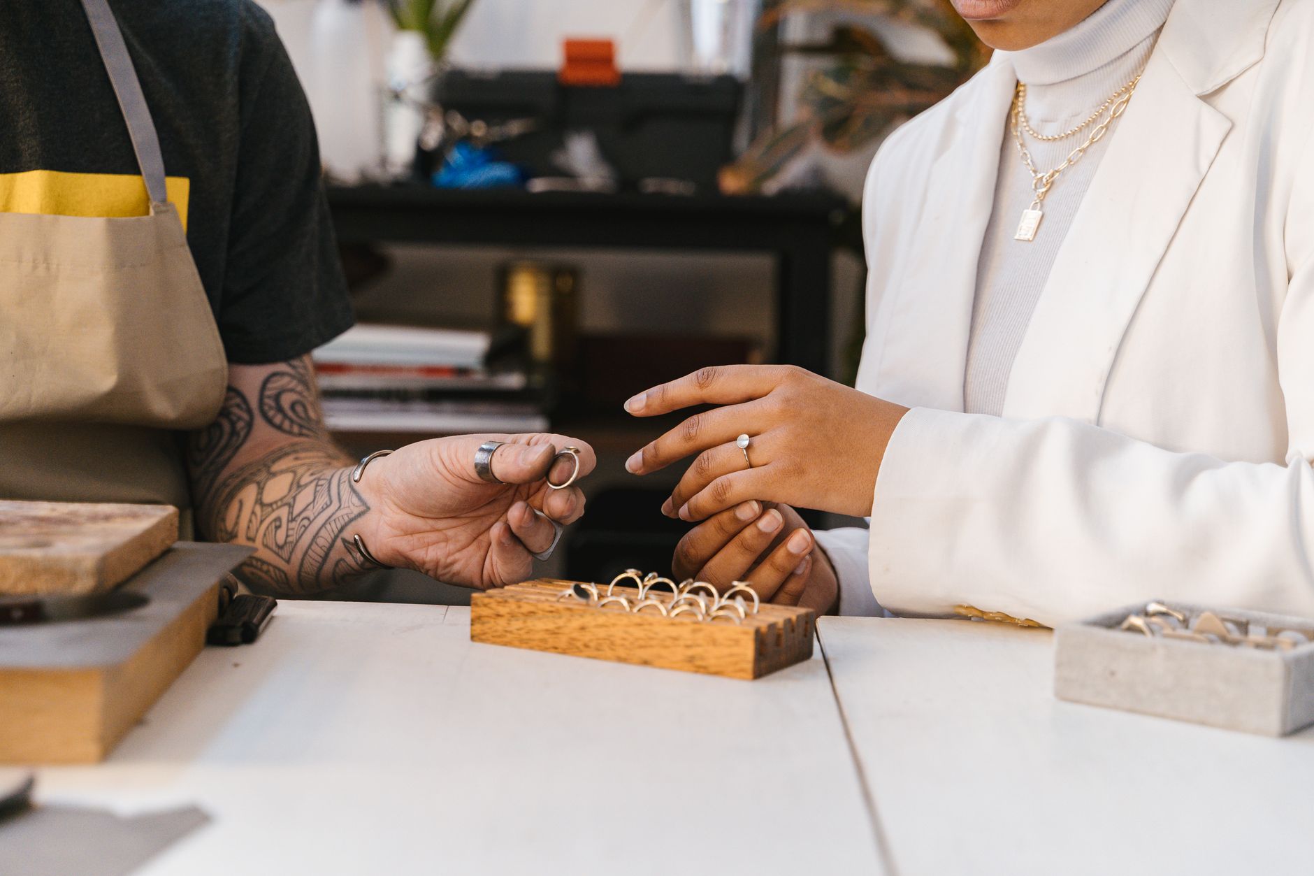 Penhor de joias para negativado: como funciona Close-up of hands exchanging rings in a jewelry workshop, showcasing handmade design.