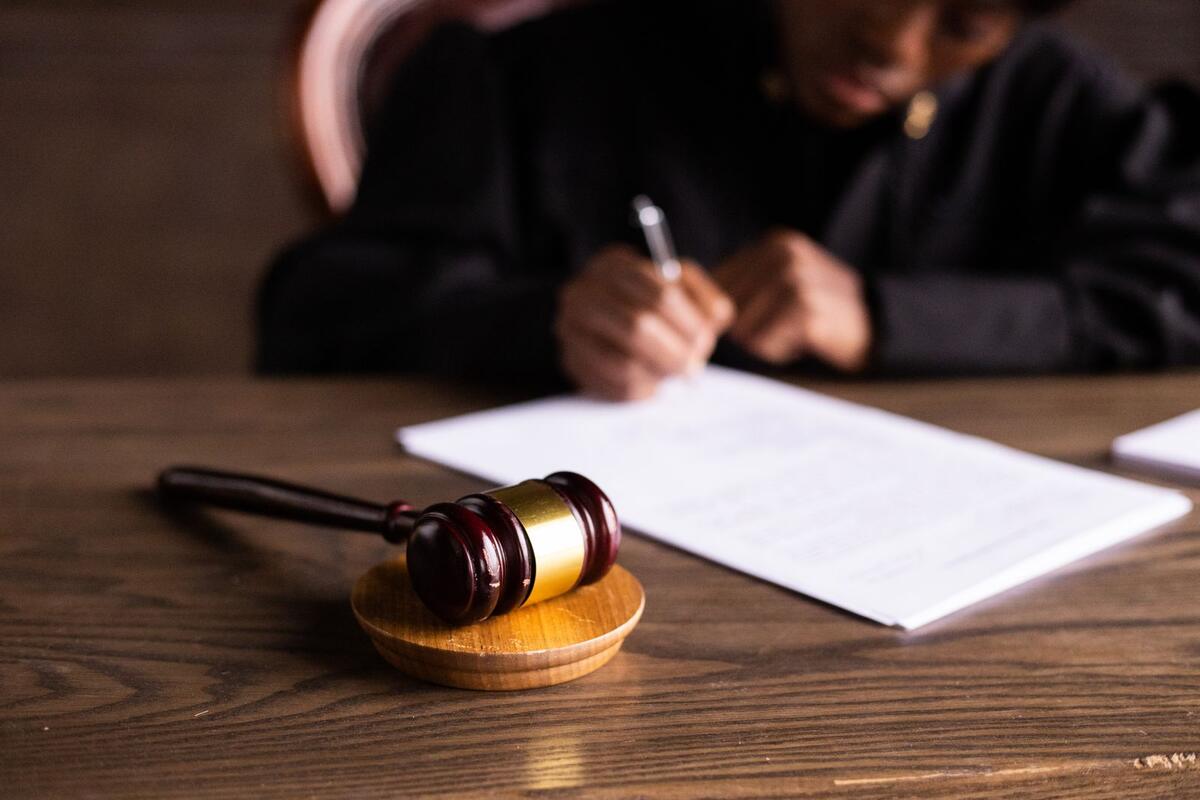 Prisão civil, desconto em folha e penhora Juiz assinando documentos em mesa com martelo, representando processo judicial