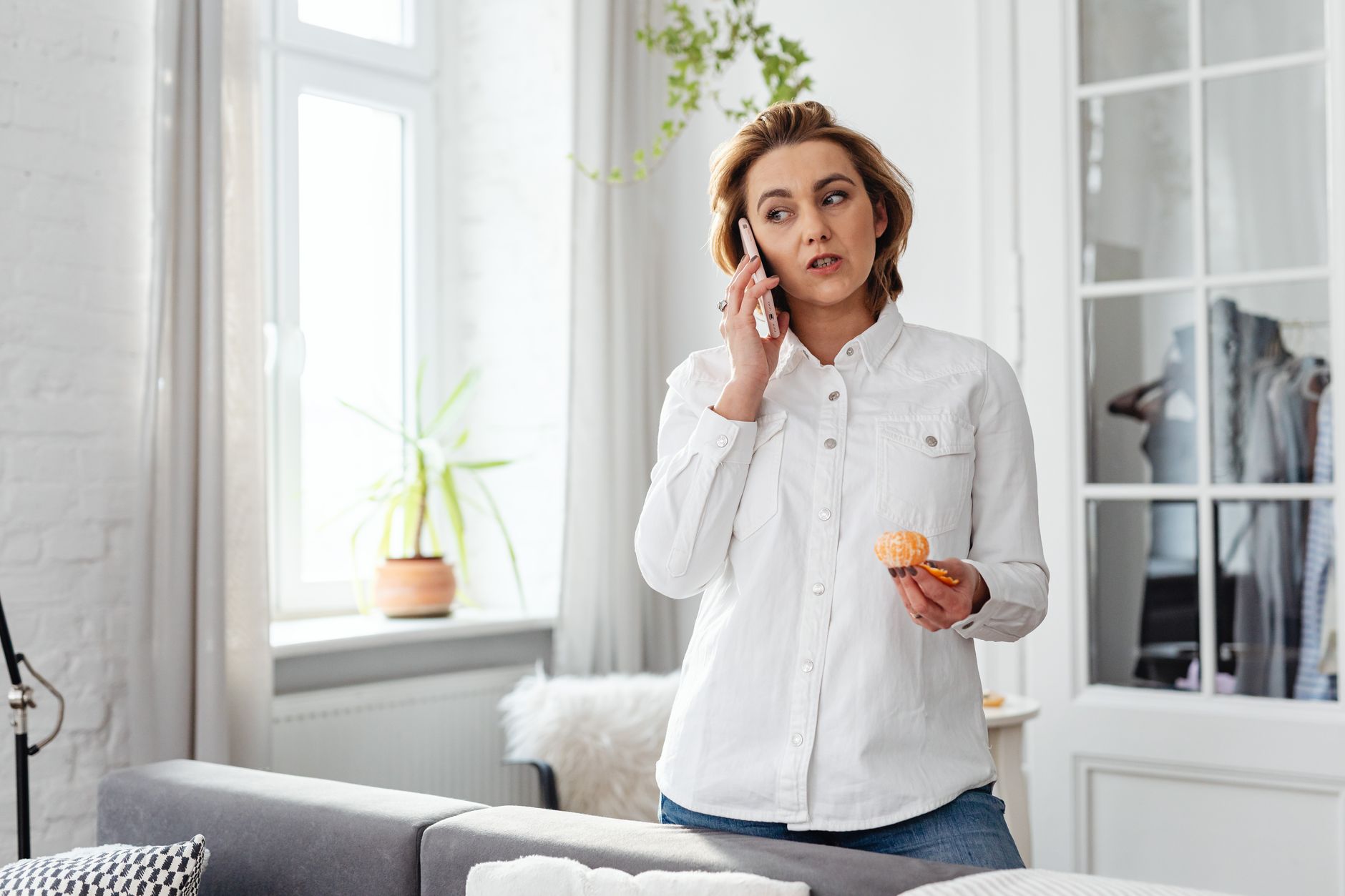 Como consultar se você tem protesto em cartório Woman in casual attire talking on phone while eating, in home office setting.