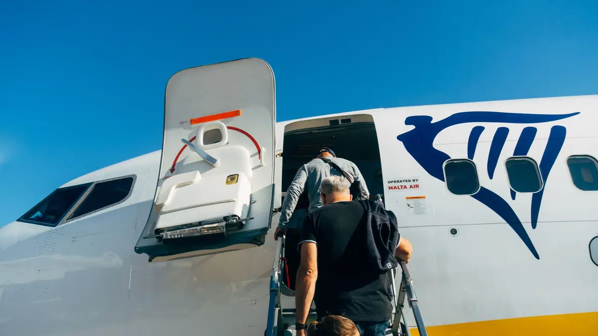 Passageiros embarcando em um avião de companhia low-cost sob céu azul