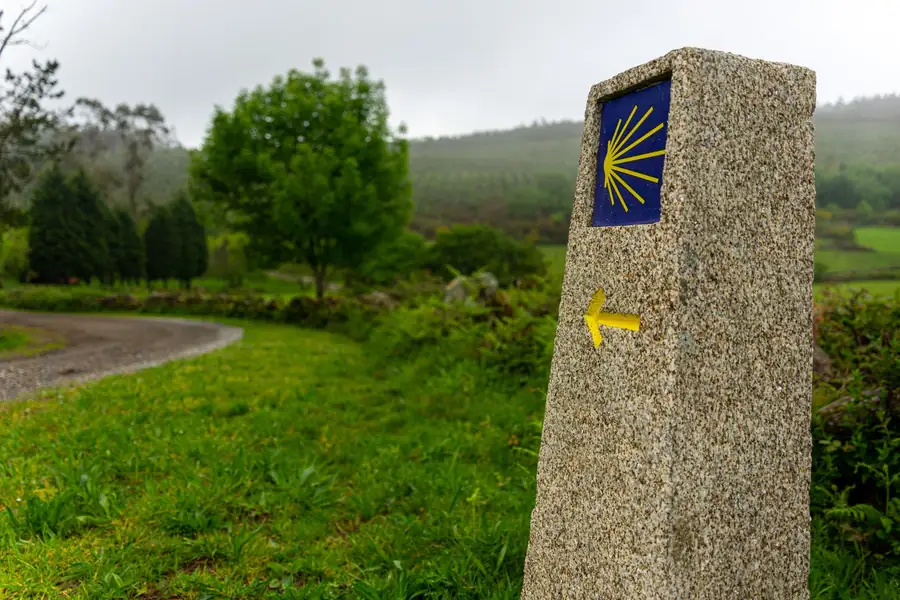 Trilha de pedra em meio ao campo com uma sinalização do Caminho de Santiago Trilha de pedra em meio ao campo com uma sinalização do Caminho de Santiago