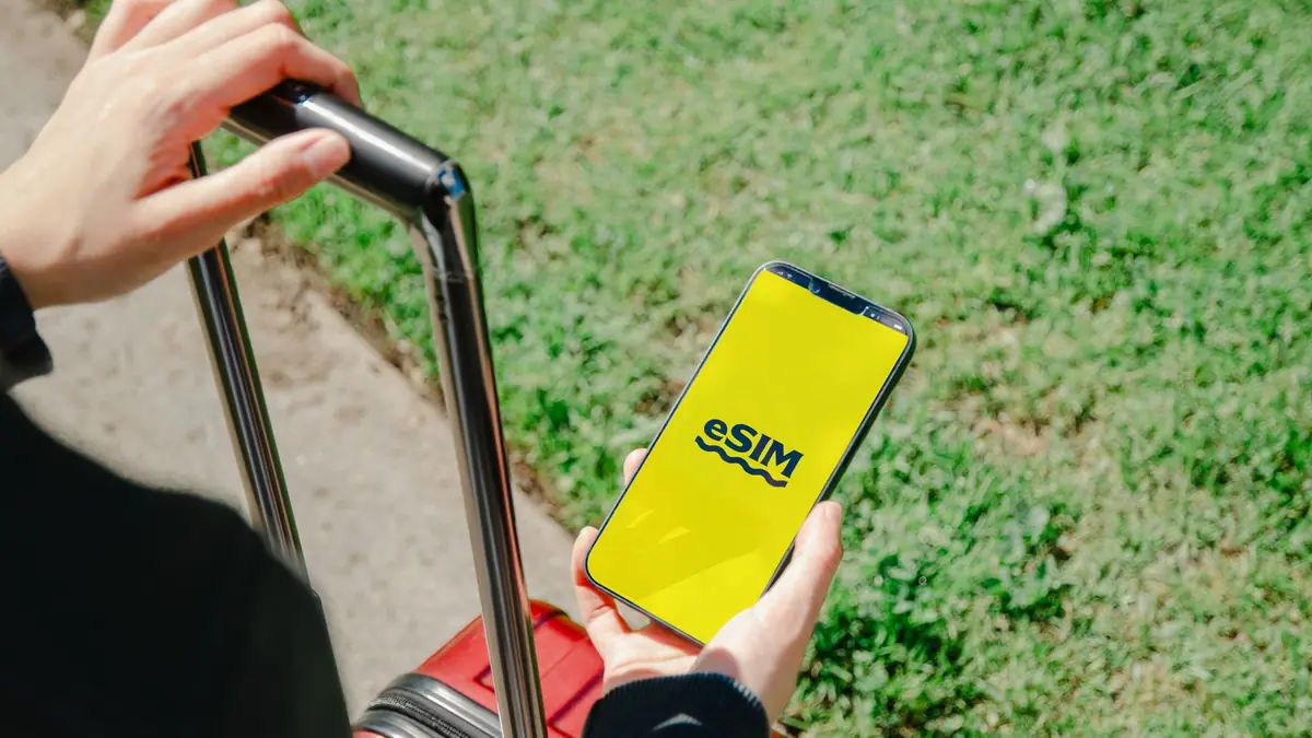 Viajante com um smartphone mostrando um plano eSIM ao lado da bagagem